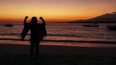 Gün batımında sahilde bir kadın silueti