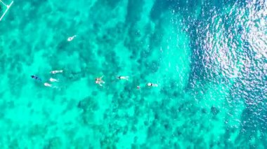 Turistler turkuaz suda yüzüyor ve şnorkelle yüzüyorlar. Endonezya, Bali 'de yaz deniz manzarası.