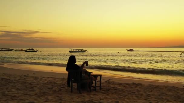 Szczęśliwa Kobieta Siedzi Krześle Plaży Zachodzie Słońca — Wideo stockowe