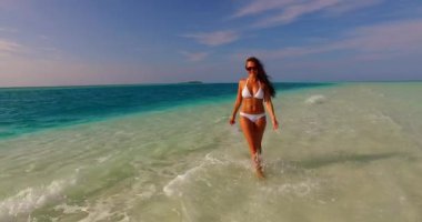 Maldivler 'de deniz kenarında beyaz bikinili genç bir kadın..