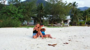 Gülümseyen çekici genç bayan arkadaşlar tropik adanın sahilinde tatilin tadını çıkarıyorlar, yaz yolculuğu konsepti görüntüleri. 
