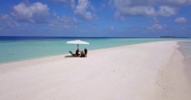 Erkek ve kadın, Maldivler 'de büyük şemsiyeler altında güneşten saklanıyor.