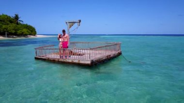 Genç adam ve kadın deniz suyunda tahta duba üzerinde yüzüyorlar. Tropik bir tatil köyünde dinlenen güzel bir çift. 