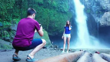Romantik iki turist, şelale ve nehir kenarında birlikte duruyorlar.   