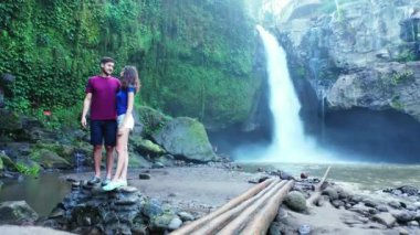 Romantik turistlerin, şelalenin yanında yan yana durdukları bir video.  