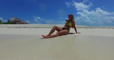 Genç sarışın kadın kumsalda güneşlenirken eğleniyor, Maldivler.