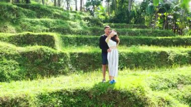 Erkek arkadaşıyla birlikte tropik adanın yeşil tarlasında yürüyen genç ve güzel bir kız. Romantik bir çift tatilin tadını çıkarıyor.  