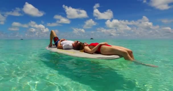 若い男と女は海のサーフボードで泳ぐ 美しいカップルは熱帯リゾートに休みます — ストック動画