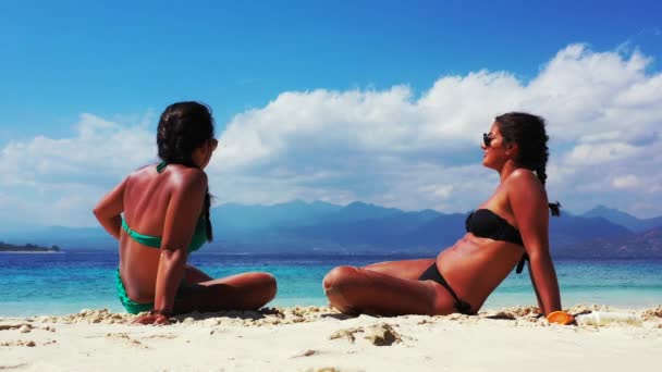 楽しい時間を過ごして砂浜で話をしている2人の女の子は — ストック動画