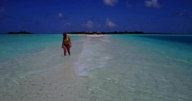 Bikini giyen, deniz tırpanı üzerinde yürüyen, bir şey düşünen bronz tenli kızın videosu. 