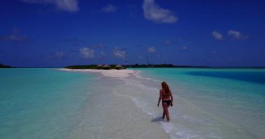 Bikini giyen, deniz tırpanı üzerinde yürüyen, bir şey düşünen bronz tenli kızın videosu. 