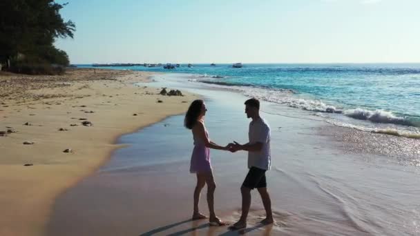 男人和他迷人的女朋友在海滩上 在碧绿水晶般的大海前悠闲自在 夏日休闲的理念 — 图库视频影像