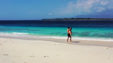 Lüks ada ve kristal okyanus videosu. Birbirine aşık çiftler sahilde yürüyor ve eğleniyorlar. 