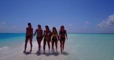 Bikinili kızların el ele tutuşup deniz tırpanı üzerinde yürüdüklerini videoya çek.