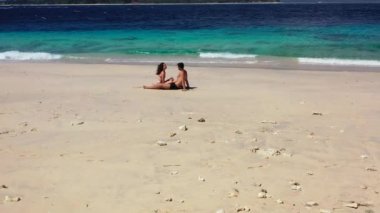  Kumsalda bir çiftin videosu. Kadın ve adam karşı karşıya oturuyor.