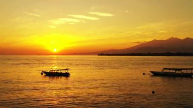 Limanda rıhtımlı tekneleri olan parlak sarı günbatımı. Bali 'de tropik tatil.