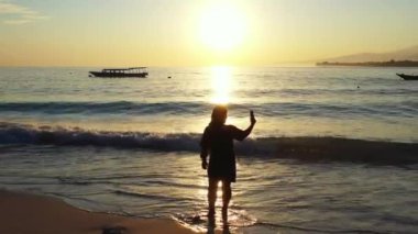 Tayland 'da gün batımında güzel plajda fotoğraf çeken bir kadın..