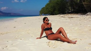 Tropik plajda güneşlenen güzel genç bir kadın.