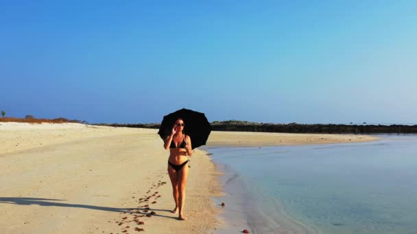 Szexi lány bikini séta esernyő homokos strandon, nyári szabadidő koncepció  