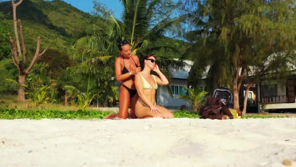 Dos Amigas Jóvenes Sentadas Costa Arenosa Del Mar Tomando Sol — Vídeos de Stock