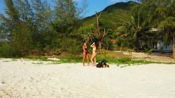 两个年轻的女朋友站在沙滩上 晒日光浴 美丽的女人在热带度假胜地休息 — 图库视频影像