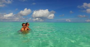 Genç adam ve kadın deniz suyunda yüzüyorlar. Tropik bir tatil köyünde dinlenen güzel bir çift.  