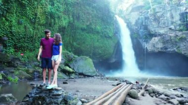 Romantik turistlerin, şelalenin yanında yan yana durdukları bir video.  
