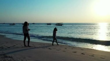 Tropikal sahilde fotoğraf çeken güzel genç kadınlar.