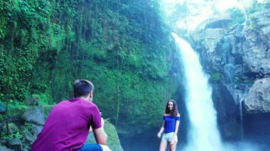 Romantik iki turist, şelale ve nehir kenarında birlikte duruyorlar.   
