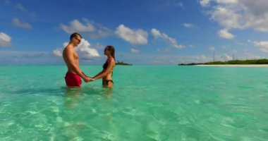 Deniz suyunda duran genç adam ve kadın. Tropik bir tatil köyünde dinlenen güzel bir çift.    