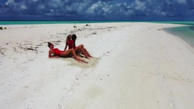 Bronzlaşmak ve tatilin tadını çıkarmak. Genç ve güzel kadınlar, bakir sahilde, berrak denizde dinleniyorlar..