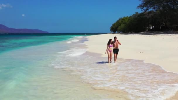 海岸線を歩き お互いを楽しむのが大好きカップルと豪華な島とクリスタル海のビデオ — ストック動画