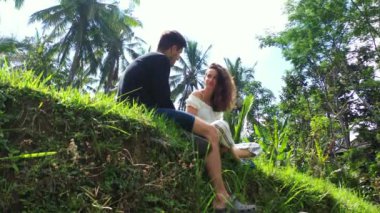 Erkek arkadaşıyla çimenlerde oturan çekici genç bir kadın, seyahat konsepti görüntüleri. 