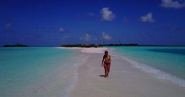 Bikini giyen, deniz tırpanı üzerinde yürüyen, bir şey düşünen bronz tenli kızın videosu. 