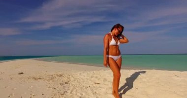 Mükemmel vücutlu güzel bir kadın plajda dinleniyor, beyaz bikini giyiyor. Bora-Bora 'da yaz tatilinin tadını çıkarıyorum..