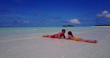 Genç bir adam ve kadın deniz kıyısında güneşleniyorlardı. Tropik bir tatil köyünde dinlenen güzel bir çift.   