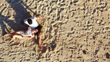 Bir adamın sevgilisiyle kumlu ada sahillerinde, romantizm ve yaz seyahati konseptinde rahatlarken çekilmiş bir video. 