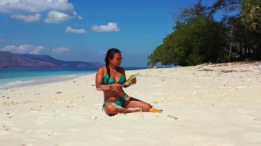 Tropik plajda dergi okuyan güzel genç bir kadın.