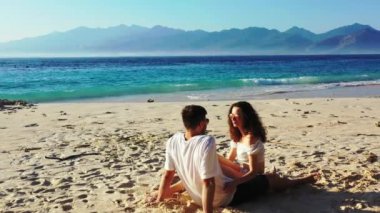 Romantik çift tropik sahilde oturuyor.