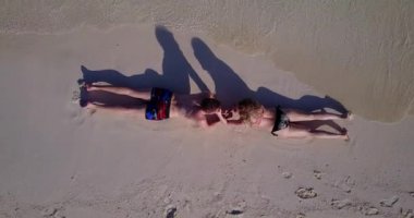 Genç bir adam ve kadın deniz kıyısında güneşleniyorlardı. Tropik bir tatil köyünde dinlenen güzel bir çift.   