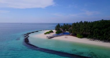 Beyaz kumlu sahil adaları, kuru palmiye yapraklı kafe çatısı, ahşap iskele ve insanların hava görüntüsü. 