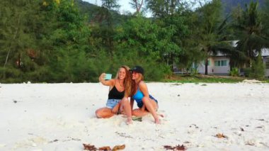 Gülümseyen çekici genç bayan arkadaşlar tropik adanın sahilinde tatilin tadını çıkarıyorlar, yaz yolculuğu konsepti görüntüleri. 