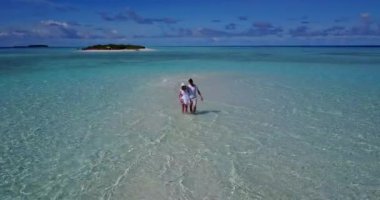 Genç bir adam ve kadın deniz suyunda yürüyorlar. Tropik bir tatil köyünde dinlenen güzel bir çift.    