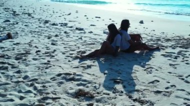 Güzel iki kız kumsalda oturuyor