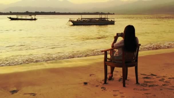 砂のビーチで椅子に座り日没の時間に — ストック動画
