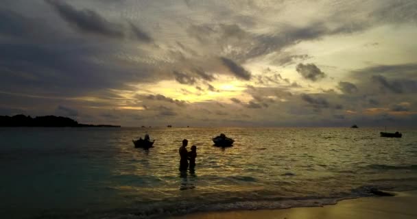 Mladý muž a žena stojí na moři a při západu slunce objímají vodu. Krásný pár odpočívající na tropické letovisko    