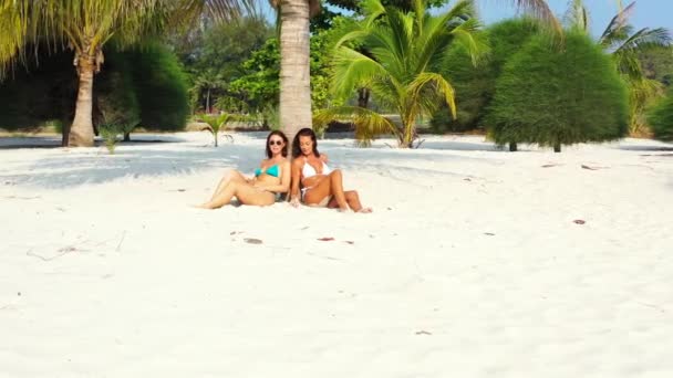 Zwei Junge Freundinnen Bikini Sitzen Der Sandküste Unter Palmen Und — Stockvideo