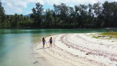 Kumlu kumsalda yürüyen kızların bir şey hakkında konuştuklarını görmek. 