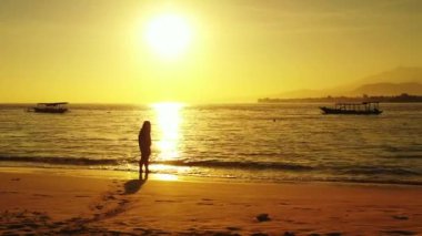 Gün batımında sahilde bir kadın silueti