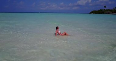 Bora Bora 'daki tropikal sahilde beyaz bikini giyen ve dinlenen genç bir kadın.